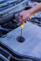 Mechanic checking and fixing a dipstick to check the oil level in car engine photo