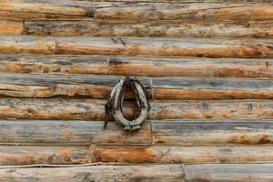 Old rusty horseshoe on woden log wall, background photo