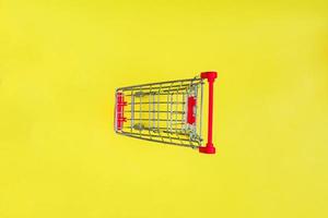 Empty shopping cart on yellow background. Top view, minimal flat lay. photo