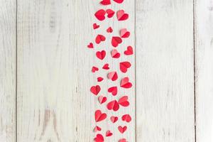 Plenty of cut out paper red hearts on wooden backround, top view, flat lay photo