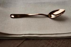 Close up of cloth napkin of beige color and served tea spoon on wooden table. photo