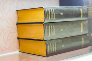 pile of old books with black retro cover on shelf. Selective focus photo