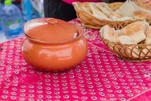 close up of clay bowl and basket with pita on the table, outdoors photo