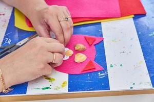 woman create a cat from red felt and sea shells at the workshop photo