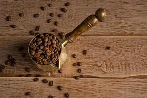 Top view of fresh roasted coffe beans in  cezve traditional turkish coffee pot on wooden table. photo