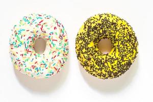 White vanila and yellow banana frosted donuts with colorful sprinkles  on white background. photo