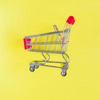 Empty shopping cart on yellow background. Top view, minimal flat lay. photo