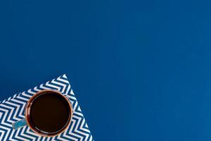 top view of cup of black coffe on blue background with copy space. photo