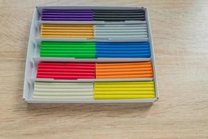 Set of multicolored plasticine bars for modeling on wooden table. Top view, eduction and creativity concept photo