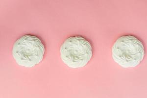 top view of homemade white air meringues on pink background photo