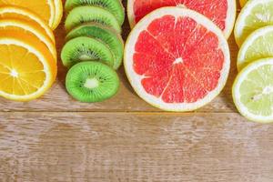 frame with slice of oranges, lemons, kiwi, grapefruit pattern on wooden background. copy space. photo