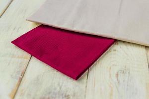 close up of cloth napkins of beige and burgundy colors on rustic white wooden table. Shallow depth of field. photo