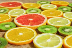 slices of oranges, lemons, kiwi, grapefruit pattern on wooden background. Fruit summer background photo