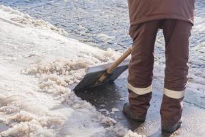 Man with snow shovel cleans city sidewalk in winter. photo