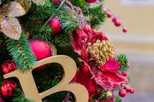 fondo de vacaciones de navidad y año nuevo. árbol de navidad decorado con bolas doradas y rojas y letra b. concepto de celebración foto