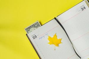 Notebook on yellow background. Shopping list on Black friday and one dollar s bookmark. Shopping and sale concept photo