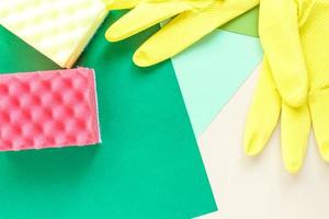 top view of yellow rubber gloves and two sponges on multicolored bright background with copy space photo