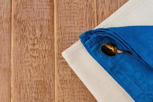 Top view of cloth napkins of beige, blue colors and served tea spoon on wooden table. photo