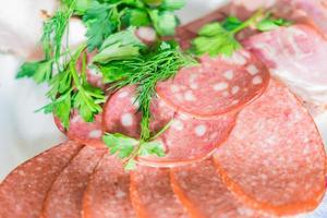 Smoked sausage salami sliced on a plate with drill and parsley. photo
