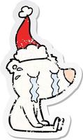 distressed sticker cartoon of a crying sitting polar bear wearing santa hat vector