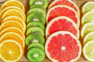 close up of slices of oranges, lemons, kiwi, grapefruit pattern on wooden background. photo