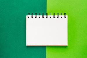 Top view of open empty spiral notebook on green colorful background photo