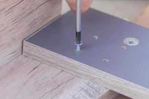 furniture assembling - Carpentry screws for a knock down wooden table. photo