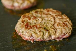 cooking meat burgers with spices on grill at home. Close up, selective focus photo