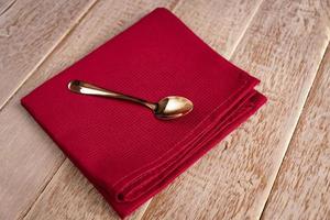 Top view of cloth napkin of beige color and served tea spoon on wooden table. photo