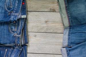 vista superior de jeans azules dispuestos sobre fondo de madera. concepto de ropa de belleza y moda foto