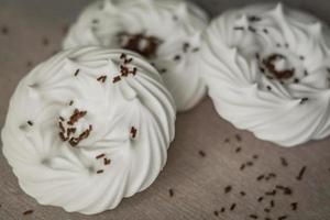 homemade white air meringues and chocolate confectionery decorations on  on parchment paper. photo