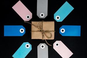 caja de regalo hecha a mano envuelta en papel artesanal con etiquetas de papel gris, rosa y valor alrededor foto