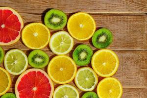 frame with slices of oranges, lemons, kiwi, grapefruit pattern on wooden background. Copy space photo