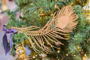 Christmas and New Year holidays background.  Christmas tree decorated with gpld feather. Celebration concept photo