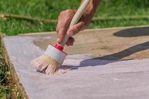 Workers hand holding a brush and puts primer on concrete floor. Garden repairs and construction. photo