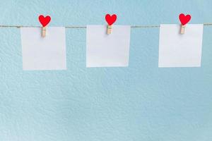 Red Valentine's love hearts pins hanging on natural cord against blue background. Mock up concept for your text photo