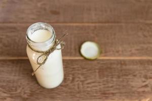 Open bottle of fresh milk on wooden background. Natural dietary product. photo