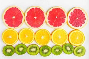 vista superior de rodajas de cítricos, kiwi, naranjas y pomelos aislados sobre fondo blanco. telón de fondo de frutas, enfoque selectivo foto