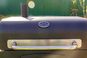 Closed bbq grill with the thermometer showing the temperaturestanding on the backyard. photo