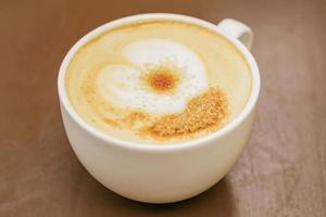 close up of big cup of freshly brewed cappuccino with soft foam and brown sugar on wooden table. photo