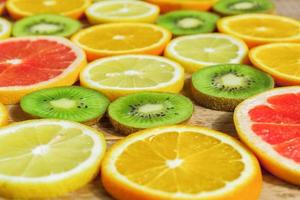 slices of oranges, lemons, kiwi, grapefruit pattern on wooden background. Fruit summer background photo