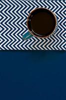 top view of cup of black coffe on textile napkin on blue background with copy space. photo