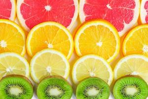 close up of citrus slice, kiwi, oranges and grapefruits isolated on white background. Fruits backdrop, selective focus photo