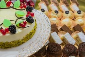 pastel de soufflé de pastelería con grosellas, moras y pistachos sobre fondo de mini postres foto