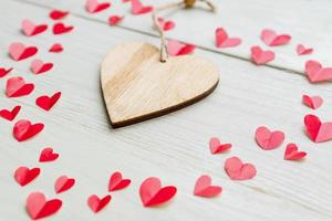 Big red heart made of cut out paper small hearts on wooden backround. Handmade decoration for Valentine's day. photo