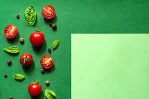 Halved Juicy Cherry Tomatoes and Basil Leaves on a green background. Concept for healthy nutrition. Top view. Copy space. photo