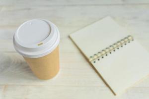 craft paper coffee cup and open notebook diary with copy space on wooden table photo