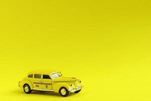viejo taxi de coche de juguete amarillo retro sobre fondo amarillo con espacio de copia. concepto de viaje foto
