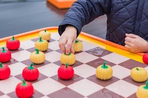 little boy in blue anorak playing pumpkin checkers with a man outdoors photo