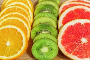 close up of slices of oranges, lemons, kiwi, grapefruit pattern on wooden background. photo